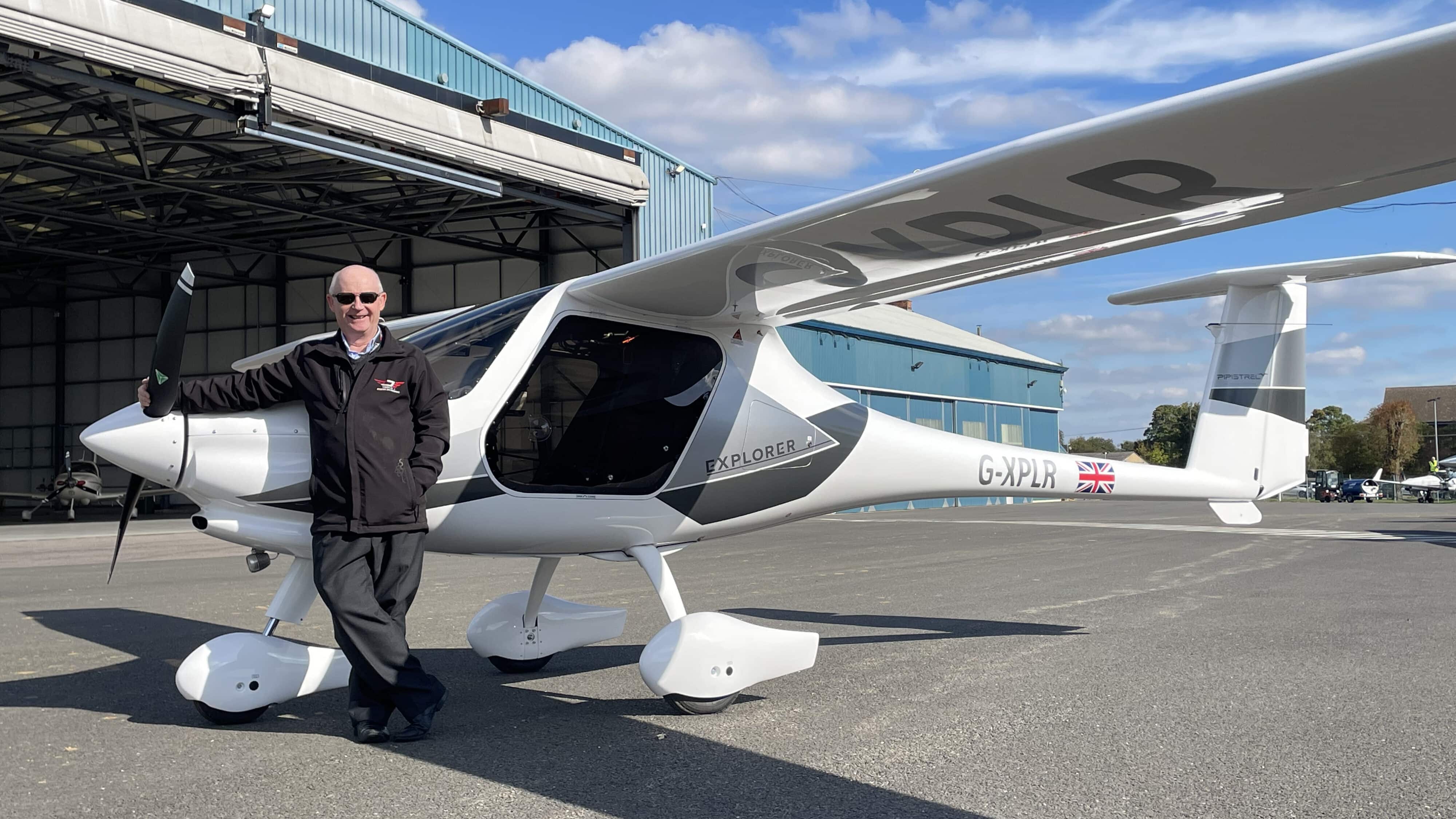 Triple Jae announced as new distributor. Man posing with Explorer aircraft on ground.